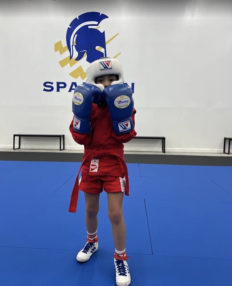 Young student in a Sambo uniform and headgear in a fighting stance
