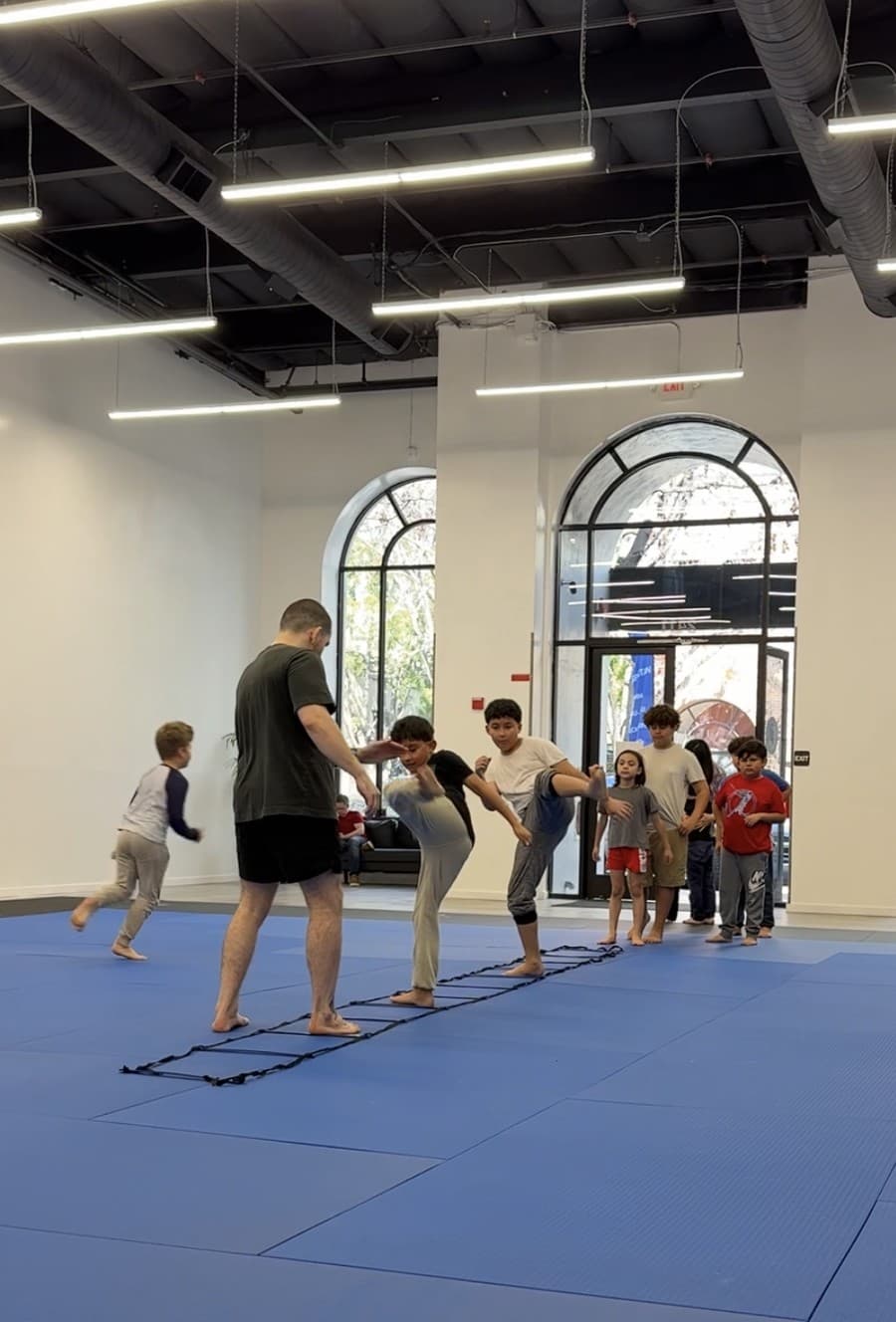 Coach running kids through an agility ladder drill